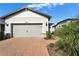 Two-car garage with gray doors and brick driveway of a lovely home at 19195 under sunny skies at 19195 Iron Topsail Isle, Land O Lakes, FL 34638