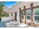 Exterior view featuring light-colored columns, a dark door, and framed windows, enhanced by a clean, stone-tiled area at 115 N Blvd Of The Presidents, Sarasota, FL 34236