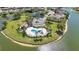 An aerial view of a resort-style community pool and clubhouse on the shores of a lake surrounded by palm trees at 2640 Suncoast Lakes Blvd, Punta Gorda, FL 33980