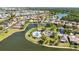 An aerial view of a community lake with a community pool and clubhouse, surrounded by numerous houses and lush landscaping at 2640 Suncoast Lakes Blvd, Punta Gorda, FL 33980