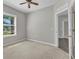 Well-lit bedroom features a ceiling fan, neutral walls, plush carpet, and a window with a view to the outside at 2640 Suncoast Lakes Blvd, Punta Gorda, FL 33980