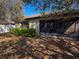 View of the backyard with screened lanai, manicured hedges, and a white fence at 675 Hartford Heights St, Spring Hill, FL 34609