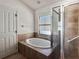 Bathroom featuring a large soaking tub, tiled surround, and shower and door at 675 Hartford Heights St, Spring Hill, FL 34609