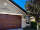 Close-up of beautiful garage exterior with mature landscaping, and a gray siding at 675 Hartford Heights St, Spring Hill, FL 34609