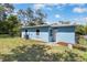 View of the home's light blue exterior and back yard with some greenery at 1724 Harbor Dr, Clearwater, FL 33755