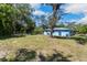 View of the home's light blue exterior from the yard with large mature trees at 1724 Harbor Dr, Clearwater, FL 33755