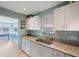 Updated kitchen with white cabinetry, granite countertops, and a view into the sunny dining nook at 5501 80Th N St # 201, St Petersburg, FL 33709