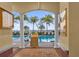View of pool with palm trees and lounge chairs through arched columns at 606 Riviera Dunes Way # 207, Palmetto, FL 34221