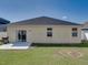 Home's backyard featuring lush green grass, a concrete patio, and a black peaked roofline at 3108 Magnolia Garden Dr, Plant City, FL 33567