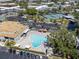 Overhead shot of a kidney-shaped community pool with chairs, umbrellas, parking, and a green area with tennis courts at 2210 Utopian E Dr # 314, Clearwater, FL 33763
