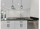 Kitchen island featuring black countertop, stainless steel sink, modern fixtures, and view to living room at 2503 Dumont Ln, North Port, FL 34286