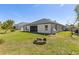 The backyard features a fire pit, screened in patio, lush lawn, and exterior view of the rear of the home at 2723 Jollivette Rd, North Port, FL 34288