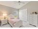 Bright bedroom features a ceiling fan, closet, and a window letting in natural light and complemented by matching white furniture at 2723 Jollivette Rd, North Port, FL 34288