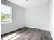 Bright, minimalist bedroom offers sleek floors, a window with sun, and neutral walls at 23113 Brewer Ave, Punta Gorda, FL 33980