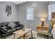 Cozy living room area featuring black leather sofa, wood-look tile flooring, and stylish accent pieces at 2912 W Frierson W Ave, Tampa, FL 33614