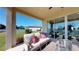 Relaxing covered back patio with comfortable seating, a lush lawn, and a sliding glass door into the living room at 9176 Players Dr, Weeki Wachee, FL 34613