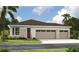 Charming one-story home featuring a three car garage, stone accents, and lush green landscaping at 9176 Players Dr, Weeki Wachee, FL 34613