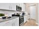 Modern kitchen featuring white cabinets, stainless steel appliances, and elegant gray countertops at 9177 Players Dr, Weeki Wachee, FL 34613