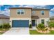 Two-story home featuring a blue garage door, tan siding, and a well-manicured front yard at 3884 Capri Coast Dr, Plant City, FL 33565
