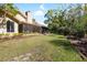 Wide view of the backyard showing the house, lawn, trees, screened in porch and greenery at 1025 Royal Troon Ct, Tarpon Springs, FL 34688