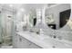 Bright bathroom with dual sinks, oval mirrors, decorative lighting and a glass-enclosed shower at 1025 Royal Troon Ct, Tarpon Springs, FL 34688