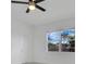 Bright bedroom features a ceiling fan, white walls, and a window offering a view of the greenery outside at 488 Sunset N Rd, Rotonda West, FL 33947
