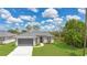 Charming single-Gathering home features a gray exterior, lush green lawn, and a two-car garage at 488 Sunset N Rd, Rotonda West, FL 33947