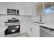 Modern kitchen with white cabinets, stainless steel appliances, and quartz countertops with a subway tile backsplash at 488 Sunset N Rd, Rotonda West, FL 33947