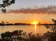 Scenic water view at sunset with reflected sunlight, framed by palm trees and lush foliage at 6009 Sea Ranch Dr # 101, Hudson, FL 34667