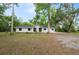 Charming single-story home features a white exterior, black roof, and a spacious front yard with mature trees at 6005 Ike Smith Rd, Plant City, FL 33565