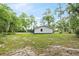 Rear exterior view of white home and dark screen porch with verdant surroundings at 6005 Ike Smith Rd, Plant City, FL 33565