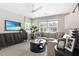 Bright living room featuring a comfortable sofa, large windows, modern entertainment center, and stylish decor at 6014 Jensen View Ave, Apollo Beach, FL 33572