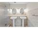 Bathroom featuring dual pedestal sinks, stylish mirrors, and a tiled glass shower at 14010 102Nd Ave, Largo, FL 33774