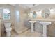 Bathroom with tiled walls, frameless shower and pedestal sinks at 14010 102Nd Ave, Largo, FL 33774