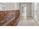 Inviting hallway with a unique brick accent wall, tile flooring, and views into the bright, neutral interior at 14010 102Nd Ave, Largo, FL 33774