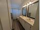 Well-lit bathroom featuring a double sink vanity and a shower with a patterned curtain at 16219 Turnbury Oak Dr, Odessa, FL 33556