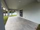 View of a covered back porch featuring tiled flooring and a sliding glass door, with a well-manicured lawn at 4146 New Milford St, North Port, FL 34288