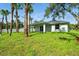 Expansive backyard with lush lawn, mature trees, and a view of the home's exterior at 4146 New Milford St, North Port, FL 34288