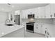 Close-up view of a modern kitchen with white cabinets, quartz countertops, and stainless steel appliances at 4146 New Milford St, North Port, FL 34288