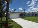 A charming house with a well-manicured lawn and a long drive, complemented by tropical palms and blue sky at 4098 New Milford St, North Port, FL 34288