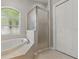 Bright bathroom featuring soaking tub under arch window, glass-enclosed shower, and closet at 19713 Ellendale Dr, Land O Lakes, FL 34638