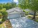 Two-story home with a three-car garage, mature landscaping, and a concrete driveway at 19713 Ellendale Dr, Land O Lakes, FL 34638