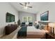 Well-lit primary bedroom suite with ceiling fan, flat-screen TV, green accents, large window and ensuite bathroom at 19713 Ellendale Dr, Land O Lakes, FL 34638