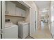 Functional laundry room with washer, dryer, storage cabinets, and tiled flooring at 13475 Crest Lake Dr, Hudson, FL 34669