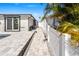 A beautiful backyard featuring a stone paver patio, with a view of the home and white fence at 5036 Bonito Dr, New Port Richey, FL 34652