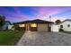 Charming single-story home featuring stone accents, a paved driveway, manicured lawn, and picturesque twilight skies at 5036 Bonito Dr, New Port Richey, FL 34652
