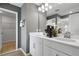 Bright bathroom showcasing double sinks, white cabinetry, modern fixtures, and wood-look flooring at 6018 Jensen View Ave, Apollo Beach, FL 33572