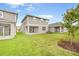 Spacious backyard with healthy green grass and the exterior of a gray two story house at 6026 Jensen View Ave, Apollo Beach, FL 33572