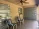 Covered patio featuring a ceiling fan, two chairs, and storm shutters at 2305 De Vore St, North Port, FL 34291