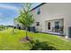 A home's backyard featuring a small patio with furniture, green grass and a tree in a manicured lawn at 5424 Companion Ln, Tampa, FL 33619